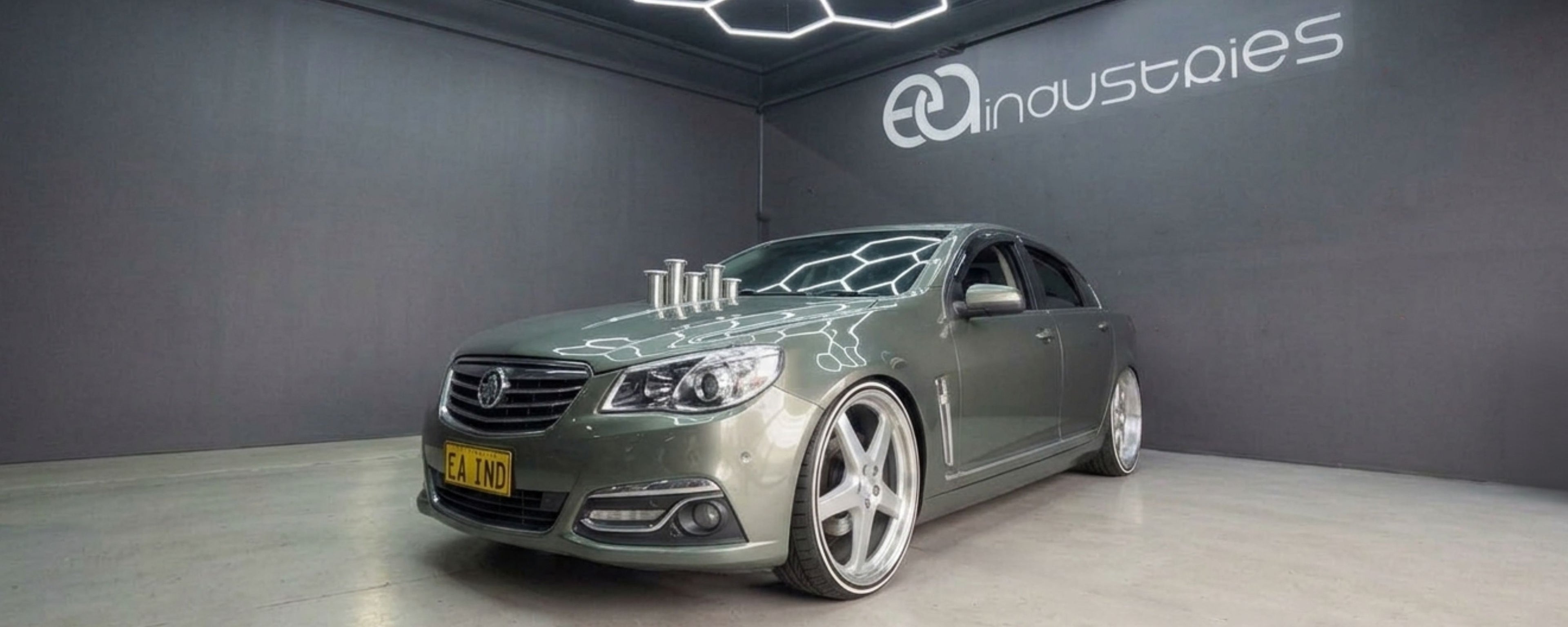 Silver car in a showroom with 'FD Industries' branding on the wall.